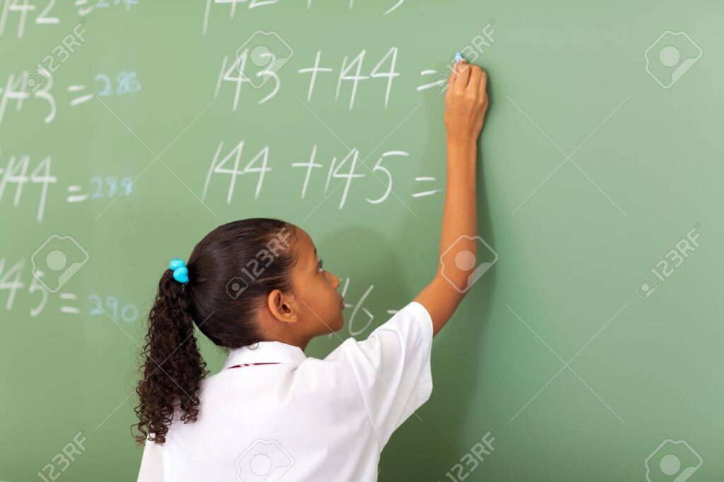 Girl solving math problems on chalkboard