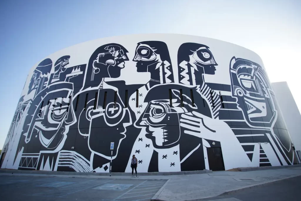 An image of graffiti on wall, depicting abstractly shaped black and white faces staring at one another
