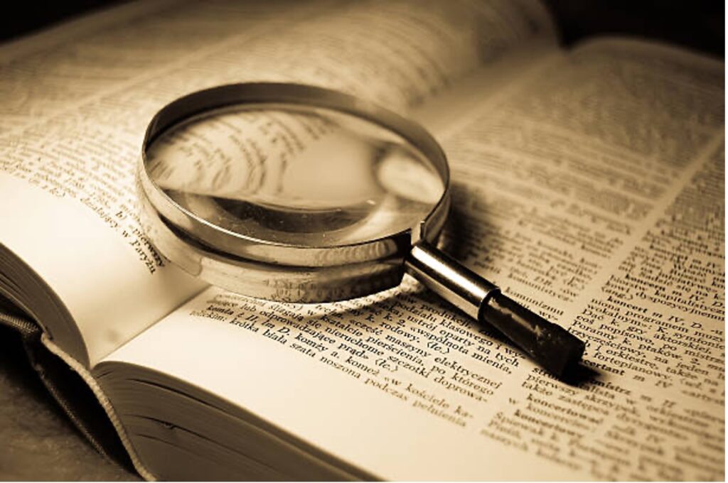 A magnifying glass placed on an open dictionary. 