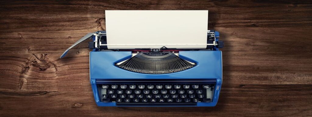 This is an image of a blue typewriter with a white piece of paper coming out of it placed on a brown wooden table.