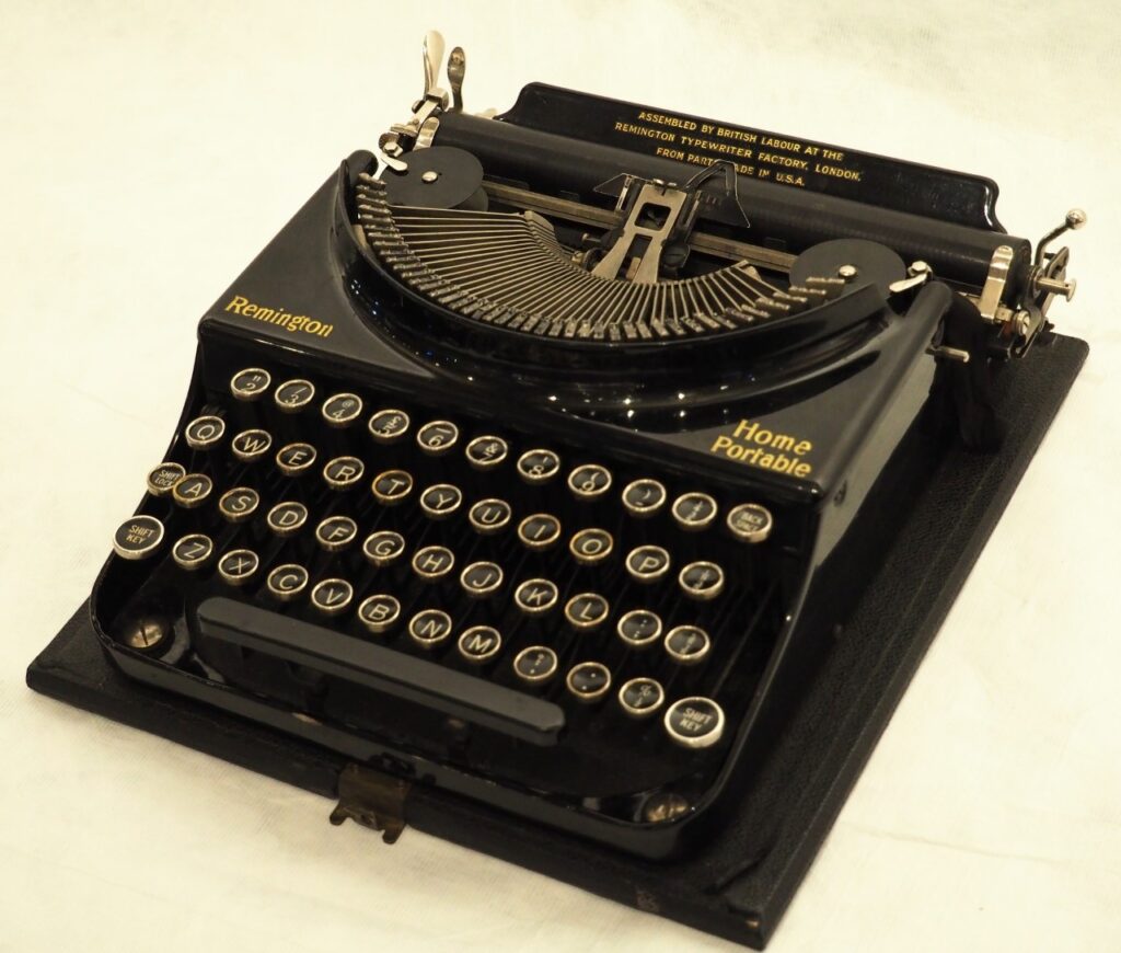 This is a photo of the Remington typewriter, with Remington written on it in yellow. The keys on the type writer spell out QWERTY.