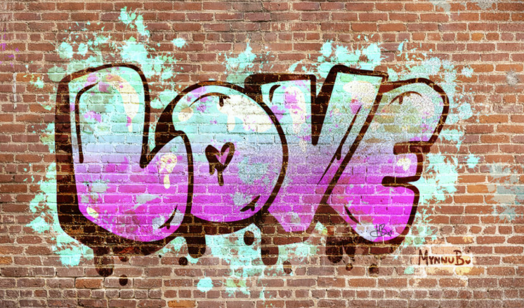 A bubbly graffiti painting of the word "love" on the wall in purple and cyan.
