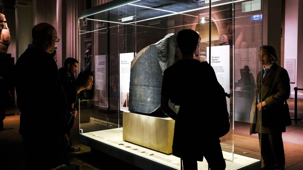 The Rosetta Stone in the British Museum with visitors around it and observing it.